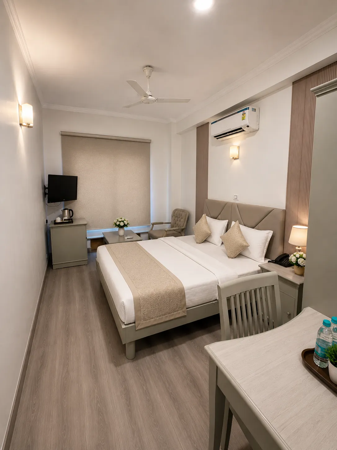 Hotel Ambica Palace — deluxe king room with velvet sofa and warm sconce lighting
